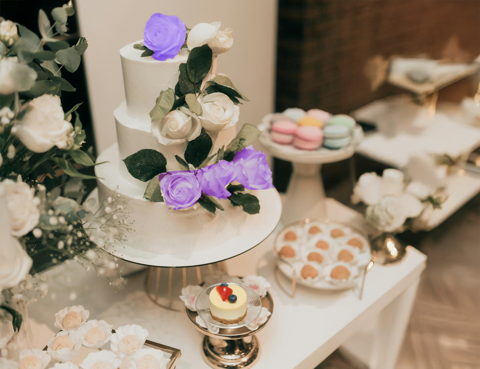 Three-tiered wedding cake adorned with white and purple roses on the display stand.